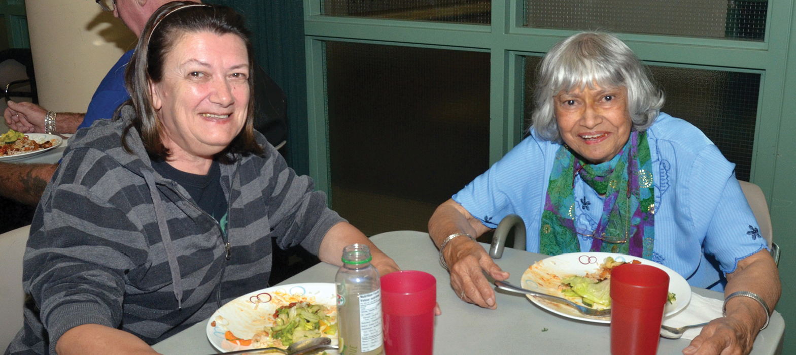 two elderly women eating at the community dinner